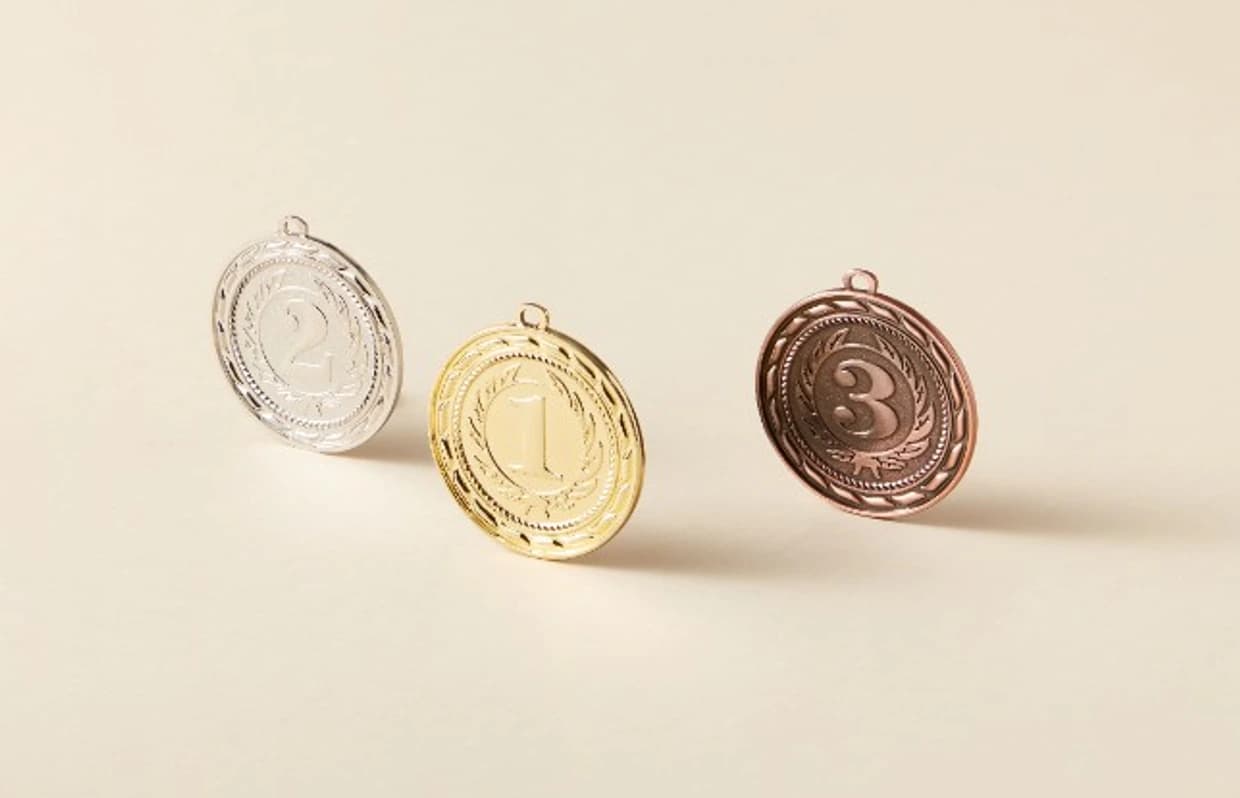 Gold, silver, and bronze ranking medals on a light surface