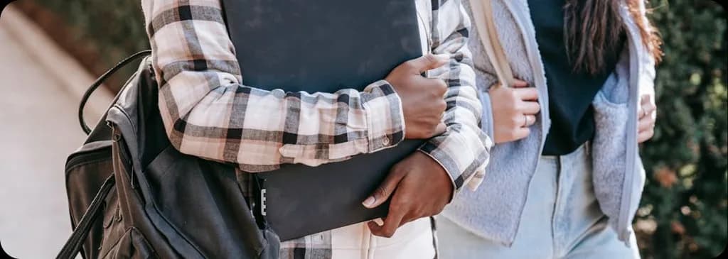 Students walking outdoors with backpacks and binders