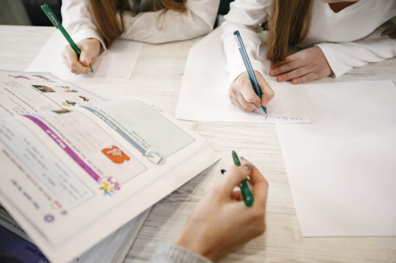 hands with pens writing on white sheet of paper